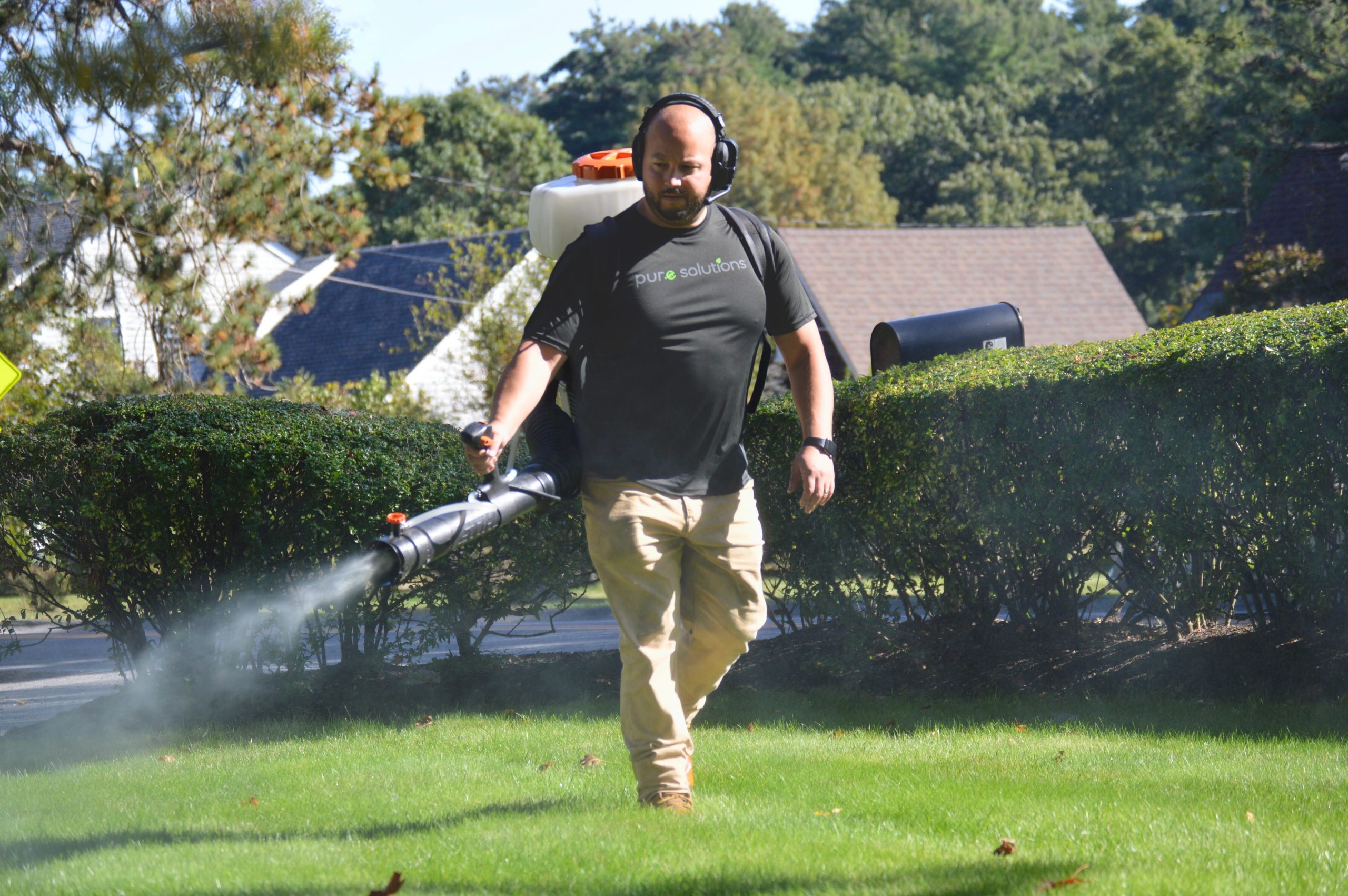 Pest technical spraying an entire property for ticks and mosquitoes including the grass