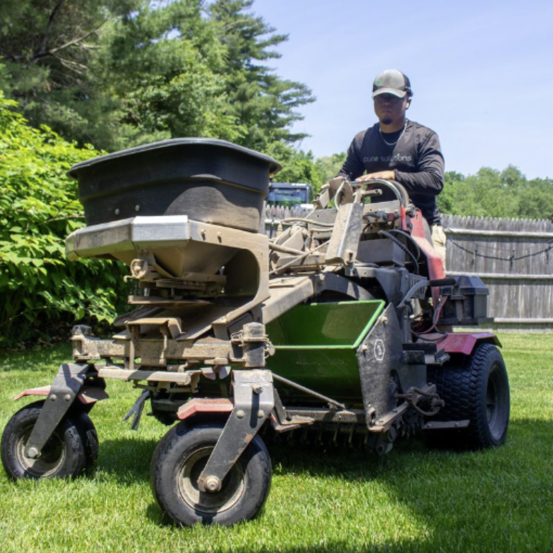 Person spreading organic lawn fertilizer on green grass