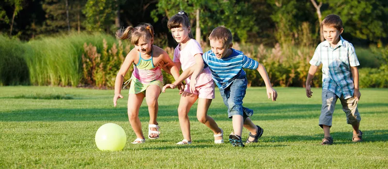Children playing soccer on a lawn